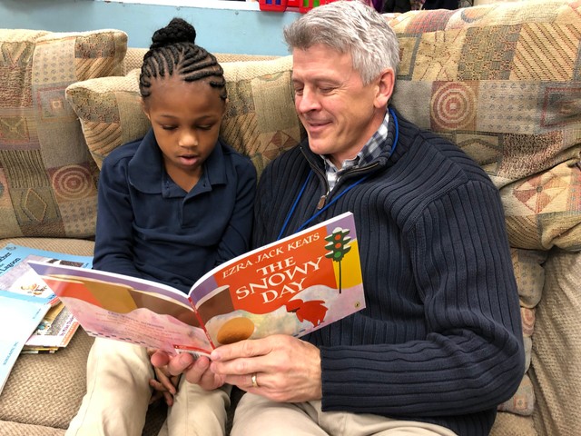 A student and reading mentor read The Snowy Day.