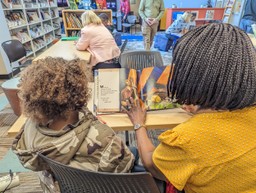 Student and reading mentor share a book by a Black author